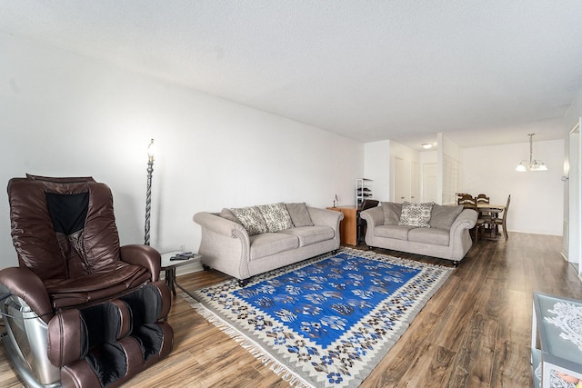 living room featuring wood-type flooring, a textured ceiling, and a notable chandelier