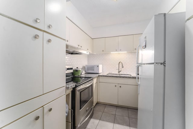 kitchen featuring tasteful backsplash, sink, light tile patterned floors, and white appliances