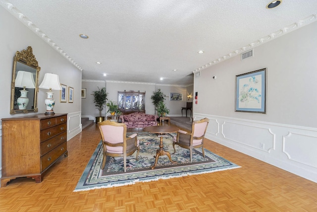 dining area featuring light parquet flooring, ornamental molding, and a textured ceiling