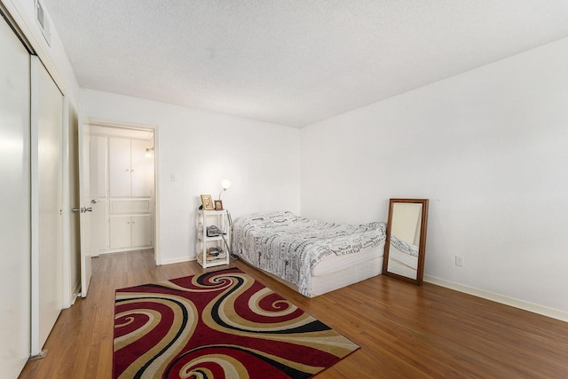 bedroom with wood-type flooring, a textured ceiling, and a closet