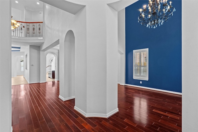 hall with dark hardwood / wood-style floors, a chandelier, and a high ceiling