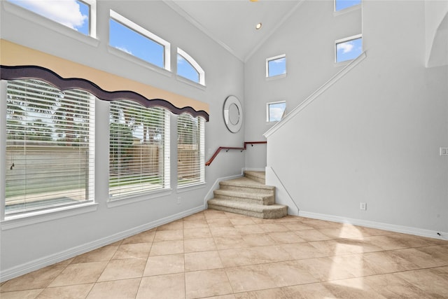 foyer with crown molding, high vaulted ceiling, and light tile patterned flooring