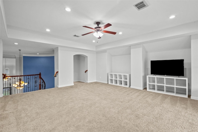 unfurnished living room featuring a raised ceiling, ceiling fan, and carpet flooring