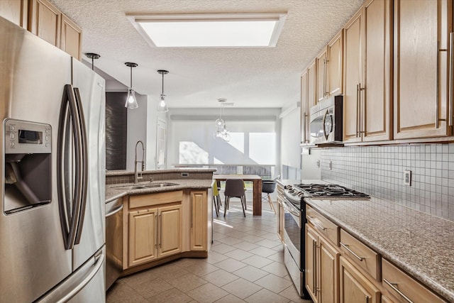 kitchen featuring appliances with stainless steel finishes, light brown cabinetry, decorative light fixtures, sink, and decorative backsplash