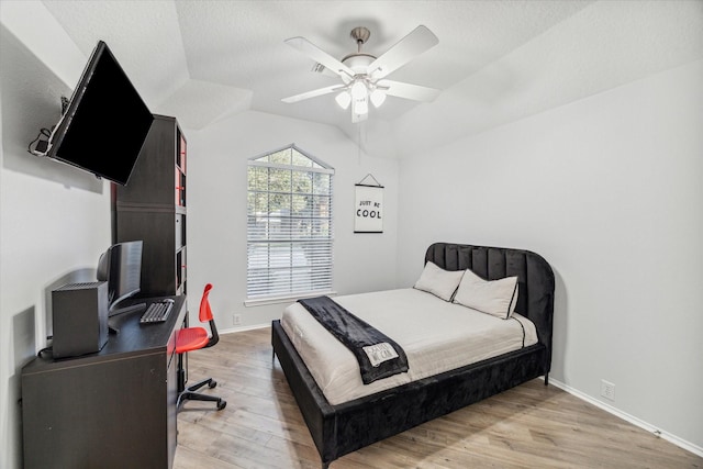 bedroom with hardwood / wood-style floors, a textured ceiling, vaulted ceiling, and ceiling fan