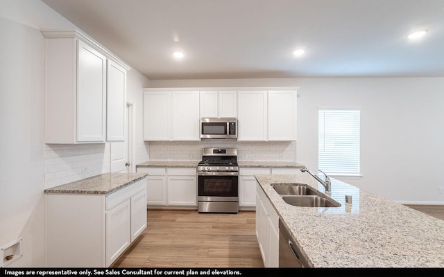 kitchen featuring sink, light hardwood / wood-style flooring, appliances with stainless steel finishes, white cabinetry, and backsplash