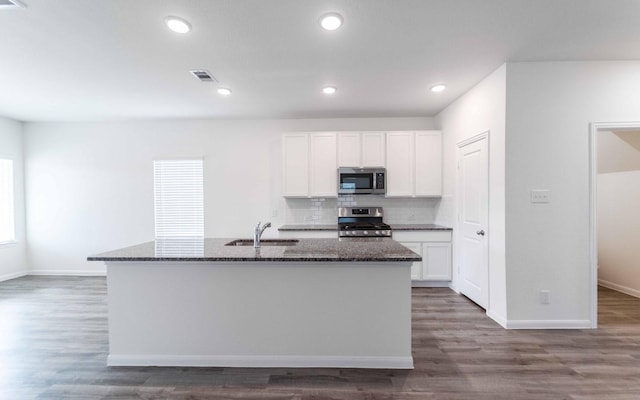 10775 Sora Dr, Willis, TX 77378 - kitchen featuring dark stone counters, white cabinetry, stainless steel appliances, and a sink