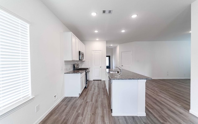 10775 Sora Dr, Willis, TX 77378 - kitchen featuring a sink, stainless steel appliances, dark stone counters, light wood-type flooring, and visible vents