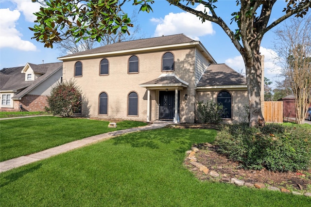 view of front of house with brick siding, fence, and a front lawn