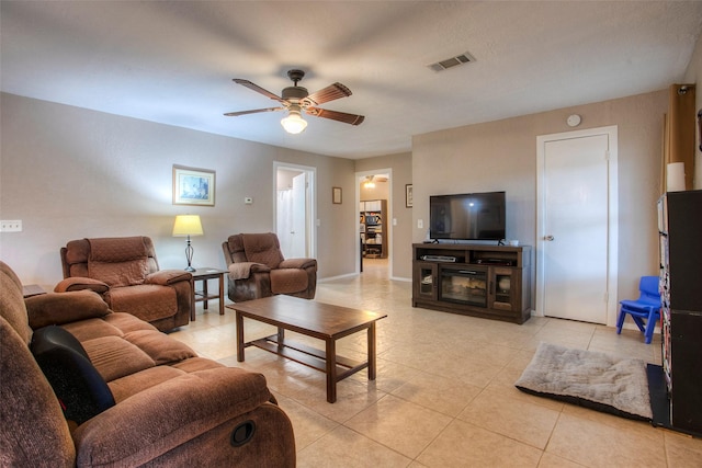 tiled living room featuring a fireplace and ceiling fan