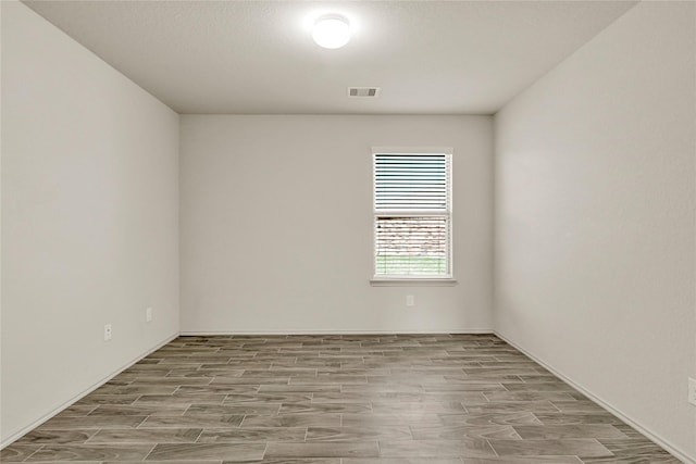 empty room with wood tiled floor and visible vents