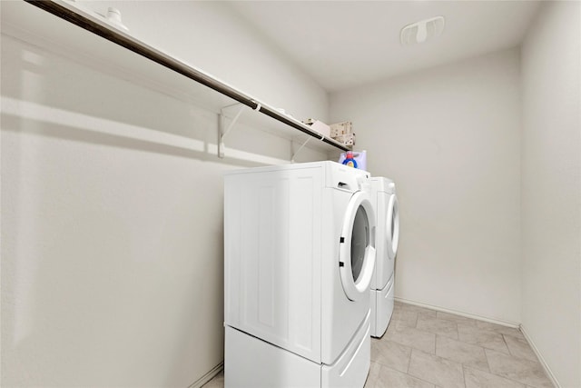 clothes washing area featuring laundry area, baseboards, and washing machine and clothes dryer