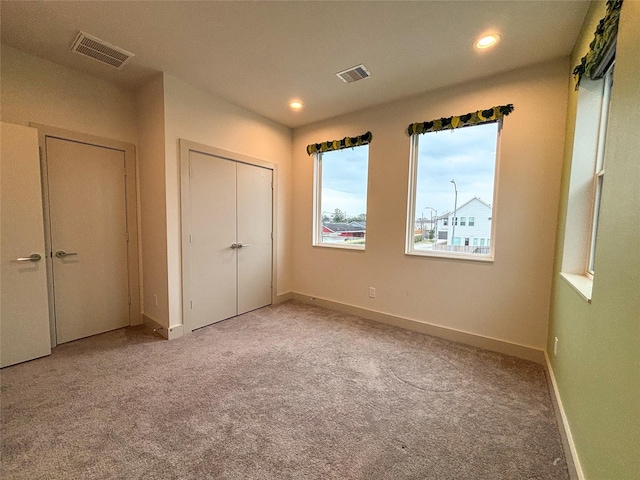 unfurnished bedroom with light colored carpet and a closet