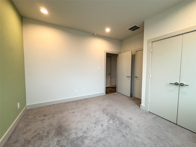 unfurnished bedroom featuring light colored carpet and a closet