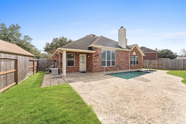 back of property with a fenced in pool, a yard, and a patio