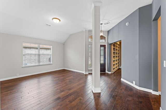 interior space featuring dark wood-type flooring, decorative columns, a textured ceiling, and vaulted ceiling