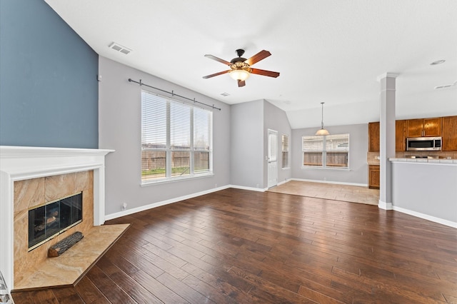 unfurnished living room with decorative columns, ceiling fan, dark hardwood / wood-style floors, and a high end fireplace