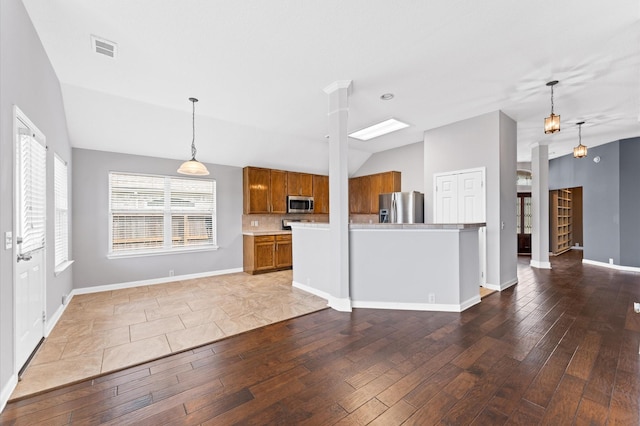 kitchen featuring pendant lighting, light hardwood / wood-style flooring, lofted ceiling, and appliances with stainless steel finishes