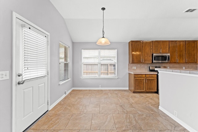 kitchen featuring stainless steel appliances, vaulted ceiling, hanging light fixtures, and backsplash