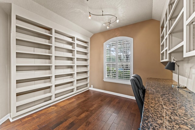 unfurnished office with dark hardwood / wood-style flooring, track lighting, lofted ceiling, and a textured ceiling