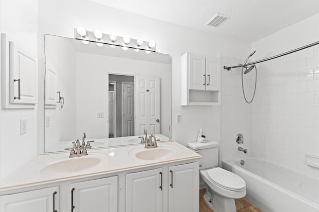 full bathroom with vanity, a textured ceiling, toilet, and tiled shower / bath