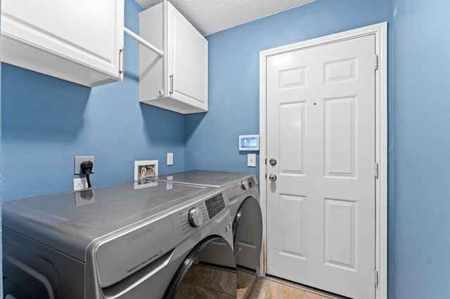 clothes washing area featuring cabinets, washing machine and dryer, and a textured ceiling