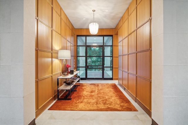 hall featuring tile walls and an inviting chandelier