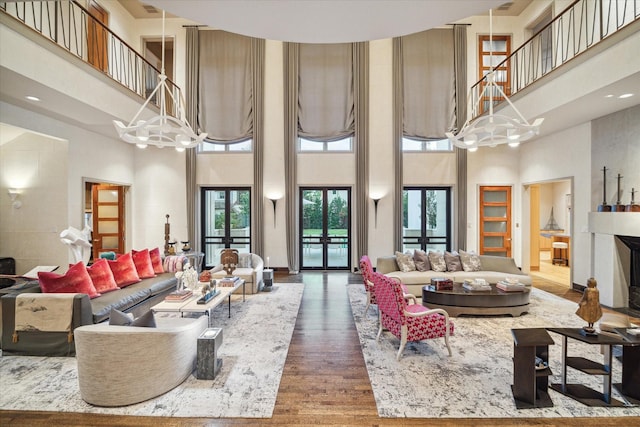 living room featuring dark wood-type flooring, a towering ceiling, french doors, and a notable chandelier