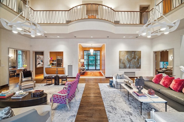 living room with an inviting chandelier, hardwood / wood-style floors, and a high ceiling