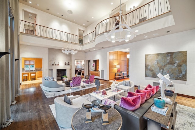 living room featuring a towering ceiling, wood-type flooring, and a chandelier