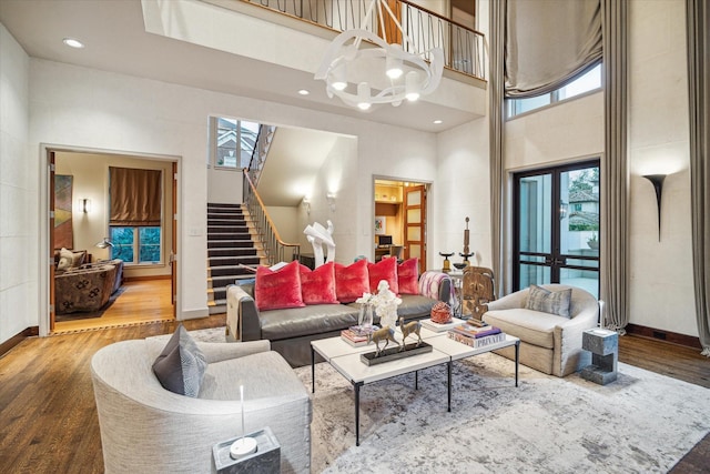 living room with a notable chandelier, a towering ceiling, and wood-type flooring