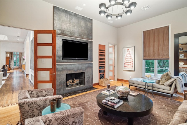 living room featuring an inviting chandelier, a large fireplace, and hardwood / wood-style floors