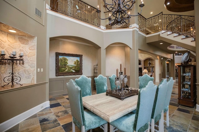 dining space with an inviting chandelier, built in features, and a high ceiling