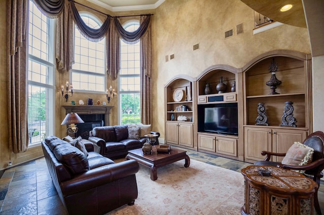 living room with a high ceiling, crown molding, plenty of natural light, and built in features