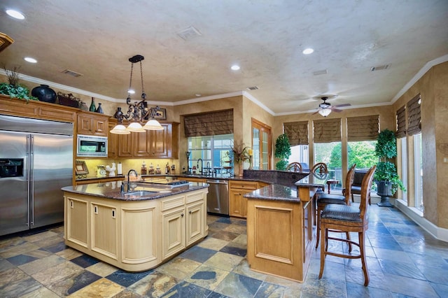 kitchen with a center island with sink, plenty of natural light, built in appliances, and decorative light fixtures