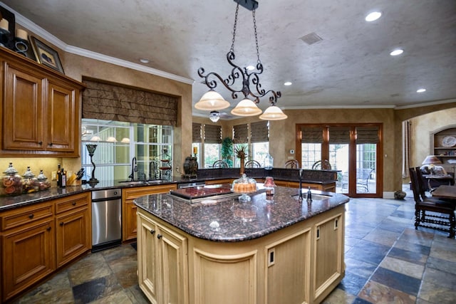 kitchen with sink, crown molding, a kitchen island with sink, hanging light fixtures, and dark stone counters