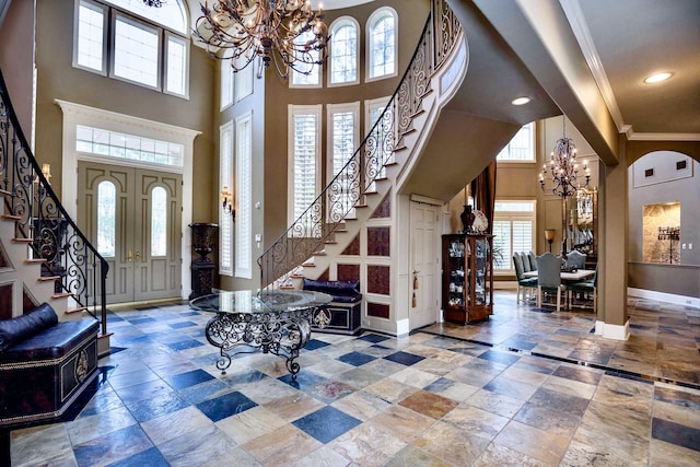 foyer entrance featuring a towering ceiling, ornamental molding, and a chandelier