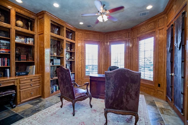 home office with ceiling fan, ornamental molding, wooden walls, and built in shelves