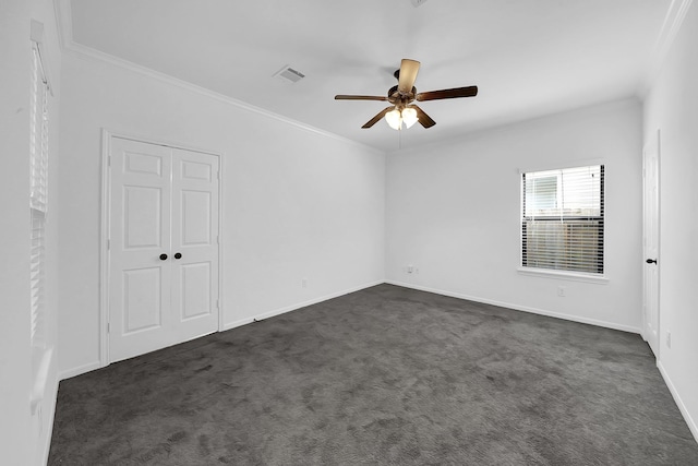 empty room featuring ornamental molding, ceiling fan, and dark carpet