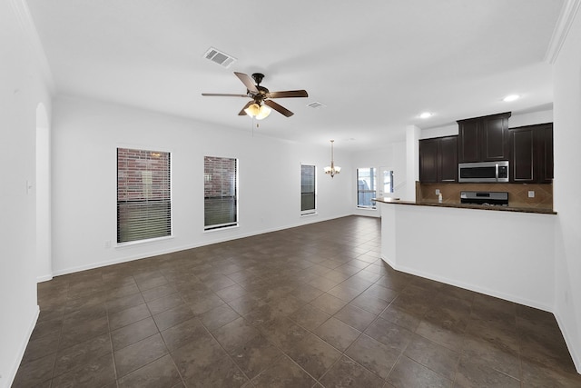 kitchen with dark brown cabinets, dark tile patterned floors, stainless steel appliances, ceiling fan with notable chandelier, and decorative backsplash