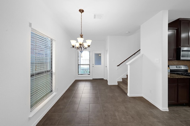 foyer entrance featuring dark tile patterned floors and a chandelier