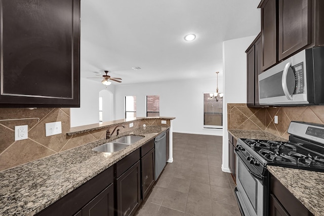 kitchen featuring ceiling fan with notable chandelier, appliances with stainless steel finishes, stone countertops, and sink