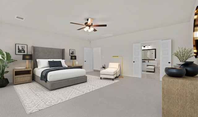 bedroom featuring ceiling fan, light colored carpet, and ensuite bath