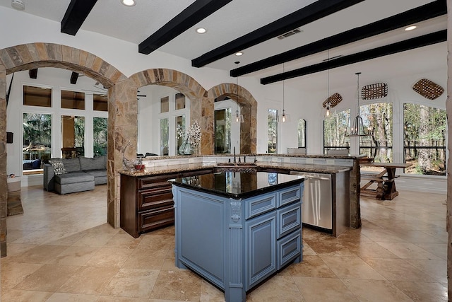 kitchen with hanging light fixtures, stainless steel dishwasher, dark stone counters, and a kitchen island