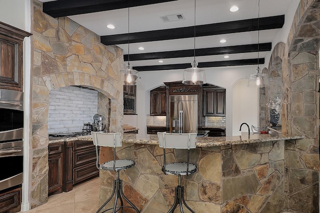 kitchen featuring stainless steel appliances, light stone countertops, hanging light fixtures, and decorative backsplash