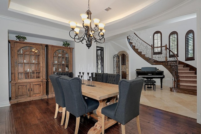 dining room with dark hardwood / wood-style floors, a tray ceiling, crown molding, and a notable chandelier