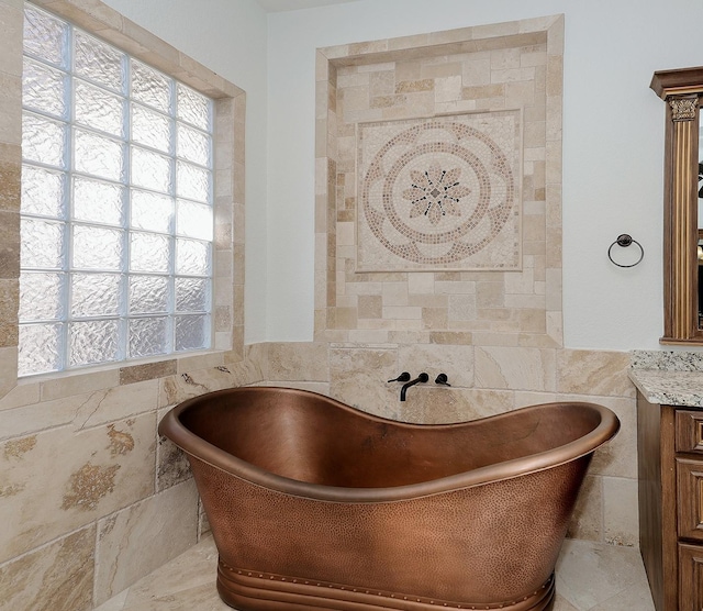 bathroom featuring tile walls, vanity, and a tub to relax in