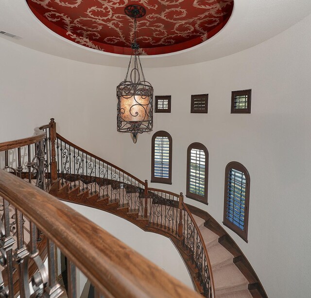 staircase with a raised ceiling and carpet