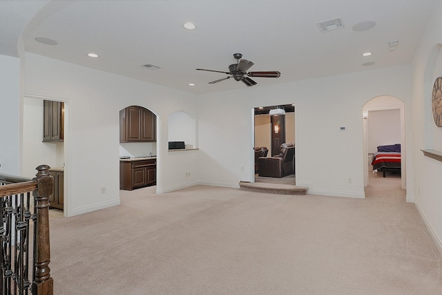 unfurnished living room featuring light colored carpet and ceiling fan