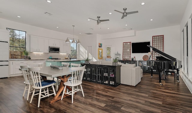 kitchen featuring dark hardwood / wood-style floors, decorative light fixtures, white cabinetry, backsplash, and a kitchen island with sink